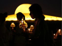 Los asistentes encendieron cirios y los monjes dieron tres vueltas alrededor del altar central del templo Dhammakaya. EFE / R. Yongrit