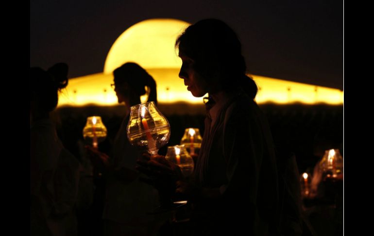 Los asistentes encendieron cirios y los monjes dieron tres vueltas alrededor del altar central del templo Dhammakaya. EFE / R. Yongrit