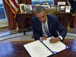 El presidente de los Estados Unidos firma en la Oficina Oval de la Casa Blanca el proyecto de ley aprobado. AP / S. Walsh