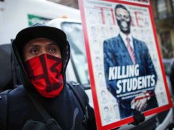 Un manifestante muestra su apoyo a los padres de los normalistas con el rostro cubierto y con un cartel contra el Peña Nieto. EFE / K. Betancur