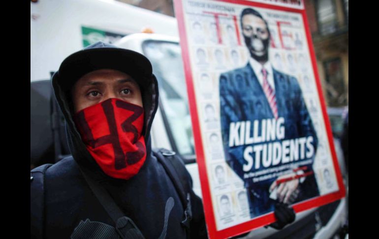 Un manifestante muestra su apoyo a los padres de los normalistas con el rostro cubierto y con un cartel contra el Peña Nieto. EFE / K. Betancur