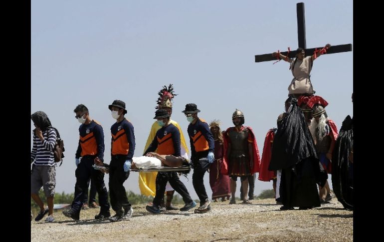 Un penitente es trasladado en camilla tras haber sido crucificado con clavos durante la representación. EFE / R. B. Tongo