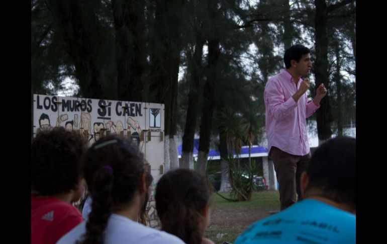 Alrededor del muro con el lema 'Los muros sí caen', los asistentes se sientan a escuchar las propuestas de Kumamoto. ESPECIAL / Pedro Kumamoto