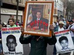 Una persona porta un retrato del gobernador con licencia con la leyenda 'asesino' en una manifestación por los 43 de Ayotzinapa. AP / ARCHIVO