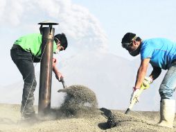 Dos personas, de las 30 que permanecen en Ensenada, quitan ceniza de un tejado para evitar su colapso, en el Sur de Chile. EFE /