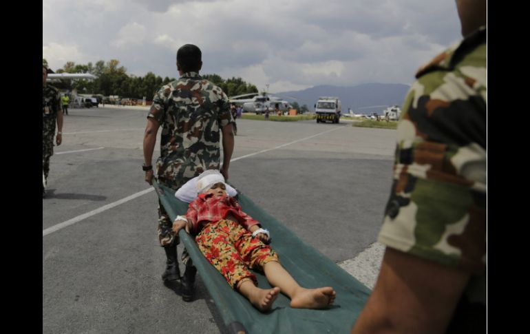 Un niño es auxiliado por militares indios que lo trasladan a un helicóptero de la Fuera Aérea. AP / A. Qadri