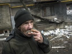 Un hombre fuma un cigarrillo junto a un edificio destruído en el este de Ucrania, donde ha sido lugar de guerra. EFE / ARCHIVO