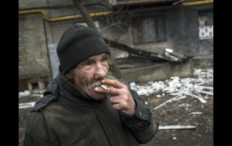 Un hombre fuma un cigarrillo junto a un edificio destruído en el este de Ucrania, donde ha sido lugar de guerra. EFE / ARCHIVO