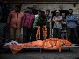 Un familiar coloca flores sobre el cuerpo de una de las víctimas del sismo antes de ser incinerado. AFP / P. Lopez