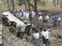 Varias personas se reúnen junto al autobús que se incendió mientras cubría una ruta corta entre las localidades de Chhatarpur y Satna. EFE / M. Pradesh