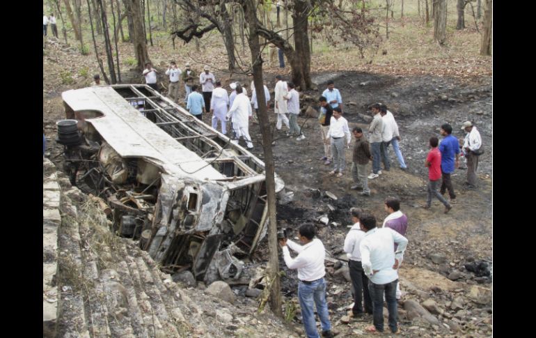 Varias personas se reúnen junto al autobús que se incendió mientras cubría una ruta corta entre las localidades de Chhatarpur y Satna. EFE / M. Pradesh