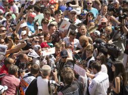 El campeón de la Fórmula Uno, Lewis Hamilton (de gorra negra), avanza entre un mar de aficionados y periodistas en la pista de Montmeló EFE / A. García