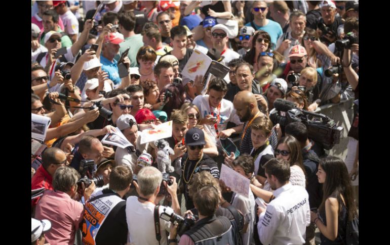 El campeón de la Fórmula Uno, Lewis Hamilton (de gorra negra), avanza entre un mar de aficionados y periodistas en la pista de Montmeló EFE / A. García