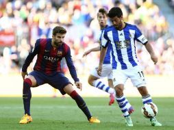 Carlos Vela (c), con el balón ante los jugadores del FC Barcelona Gerard Piqué (d) y Rafinha Alcántara (i). EFE / T. Garriga