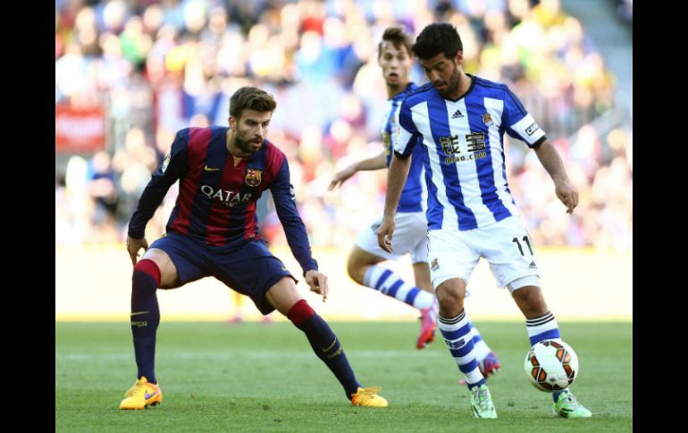 Carlos Vela (c), con el balón ante los jugadores del FC Barcelona Gerard Piqué (d) y Rafinha Alcántara (i). EFE / T. Garriga