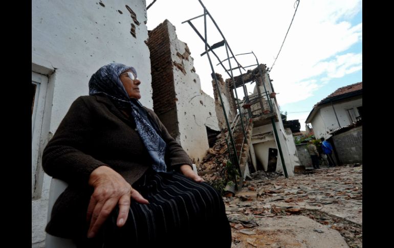 Una mujer descansa fuera de su casa, dañada durante el segundo combate entre fuerzas policiales y el grupo armado del UCK en Skopje. AFP / R. Atanasovski