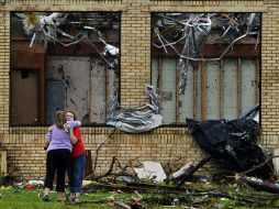 Dos mujeres se abrazan frente a la Escuela Secundaria de Van, destruída tras el fuerte tornado que el 9 de mayo golpeó el estado. EFE / L. Smith