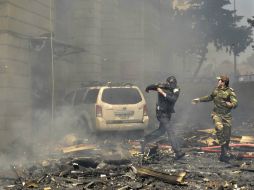 Dos policías corren escapando de los escombros que caen del edificio incendiado en Bakú. EFE / O. Azim