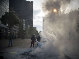 Un grupo de encapuchados quema propaganda electoral al término de la marcha por los normalistas. AFP / Y. Cortez