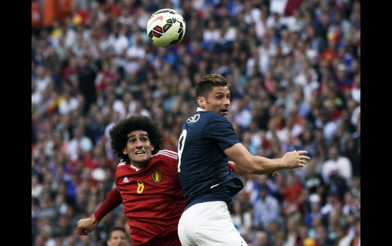 Marouane Fellaini disputa el balón con Olivier Giroud. El mediocampista del ManU hizo dos de los goles belgas. AFP / L. Venance