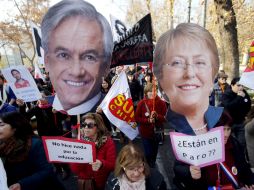 Profesores sostienen pancartas con las imágenes del expresidente Sebastián Piñera (i) y de la actual mandataria Michelle Bachelet (d). EFE / S. Silva