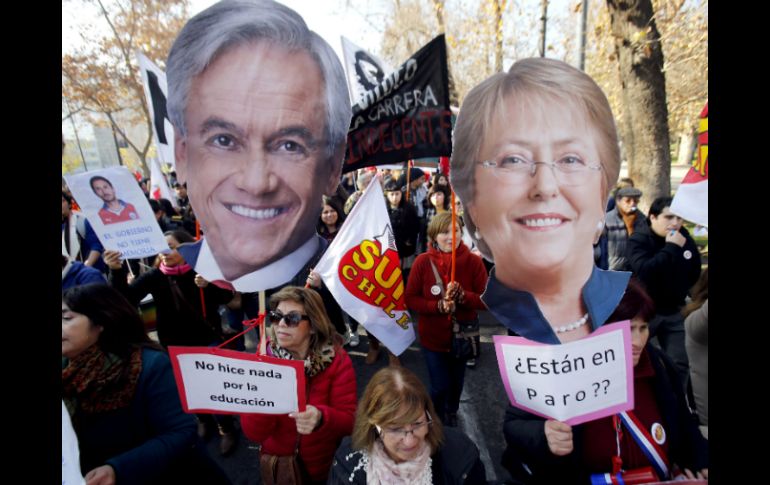 Profesores sostienen pancartas con las imágenes del expresidente Sebastián Piñera (i) y de la actual mandataria Michelle Bachelet (d). EFE / S. Silva