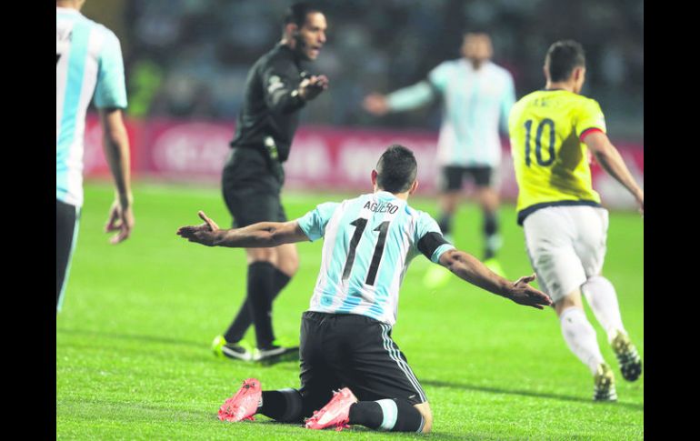 Roberto García Orozco (fondo) le pide al delantero argentino Sergio 'Kun' Agüero que siga jugando al negarle una falta. AP / N. Pisarenko