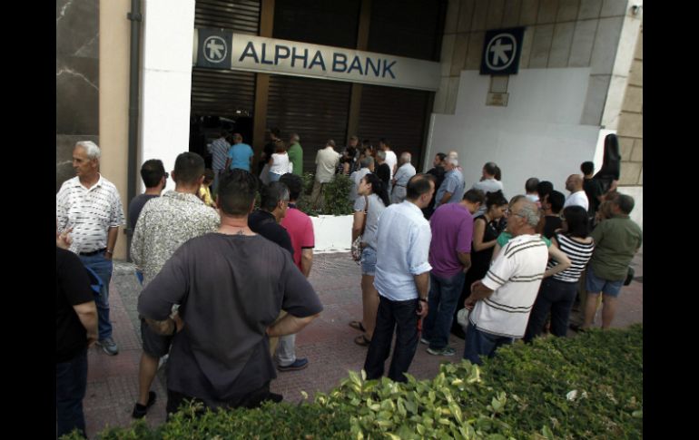 Los residentes y turistas tratan de retirar dinero en efectivo antes del cierre temporal de los bancos y el control de capitales. EFE / A. Vlachos