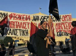 Varias personas participan en una protesta fuera del Parlamento de Atenas contra las políticas de austeridad. EFE /  O. Panagiotou