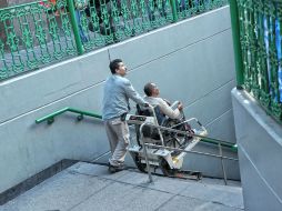 Un trabajador del Siteur ayuda a una persona a bajar las escaleras con una oruga. EL INFORMADOR / E. Barrera