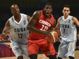 Anthony Bennett, de Canadá, se dispone a disparar soportando la marca de dos jugadores cubanos. AFP / Y. Cortez