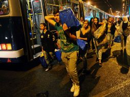 Indocumentados cargan sus pertenencias para abordar en la madrugada los autobuses que proporcionó el Gobierno húngaro. AFP /