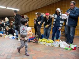 Niña húngara pasa frente a los voluntarios que dan la bienvenida a refugiados en la estación de Hamburgo. EFE / D. Reinhardt