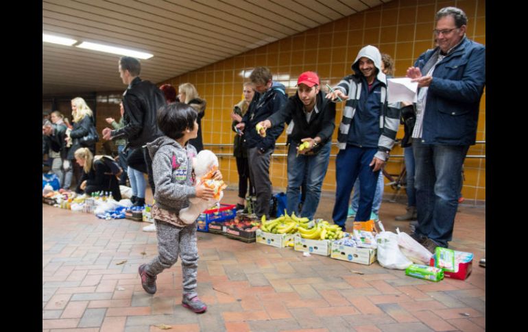 Niña húngara pasa frente a los voluntarios que dan la bienvenida a refugiados en la estación de Hamburgo. EFE / D. Reinhardt