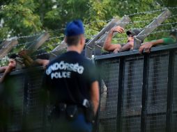 Franja de paso. Policías húngaros vigilan una flamante valla para frenar la migración en Roszque. AFP / A. Kisbenedek