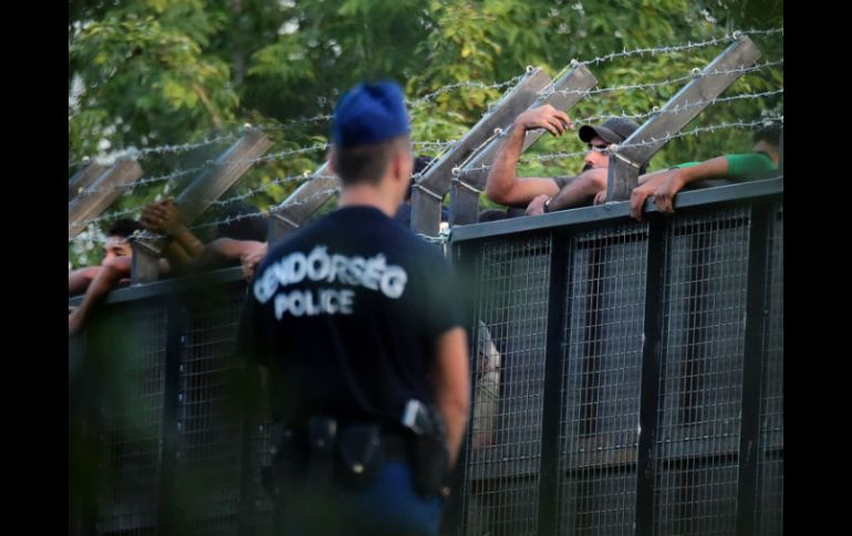 Franja de paso. Policías húngaros vigilan una flamante valla para frenar la migración en Roszque. AFP / A. Kisbenedek