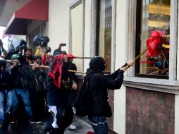 Con petardos y cohetones las personas encapuchadas, atacaron un restaurante de pollo frito y una cafetería. AFP / R. Schemidt