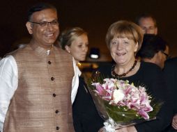 Angela Merkel fue recibida con un ramo de flores de manos del viceministro de Finanzas indio, Jayant Sinha. AP /  V. Verma