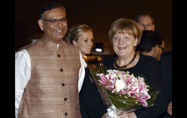 Angela Merkel fue recibida con un ramo de flores de manos del viceministro de Finanzas indio, Jayant Sinha. AP /  V. Verma