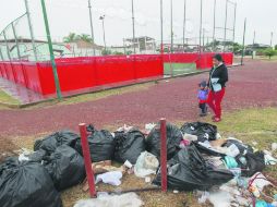 Isabel Montiel pasa con su nieto Samuel frente a varias bolsas de basura abiertas que se encuentran en una unidad deportiva de Tonalá. EL INFORMADOR / F. Atilano