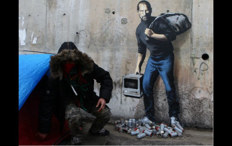 El esquivo grafitero representa a Steve Jobs, portando una bolsa negra de basura y un modelo primitivo de su computadora Macintosh. AP / M. Spingler