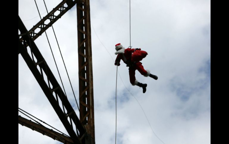 El experto en cabuyería y rapel se lanzó del puente haciendo el clásico 'Jo jo jo' del personaje navideño. EFE / E. Biba