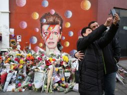 Una pareja se toma una selfie junto a una ofrenda construida a la memoria de Bowie. AFP / J. Tallis