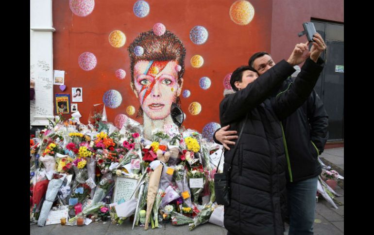 Una pareja se toma una selfie junto a una ofrenda construida a la memoria de Bowie. AFP / J. Tallis