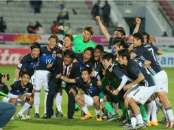 Jugadores japoneses celebran su victoria junto a su entrenador Makoto Teguramori (c-i). AFP / K. Jaafar