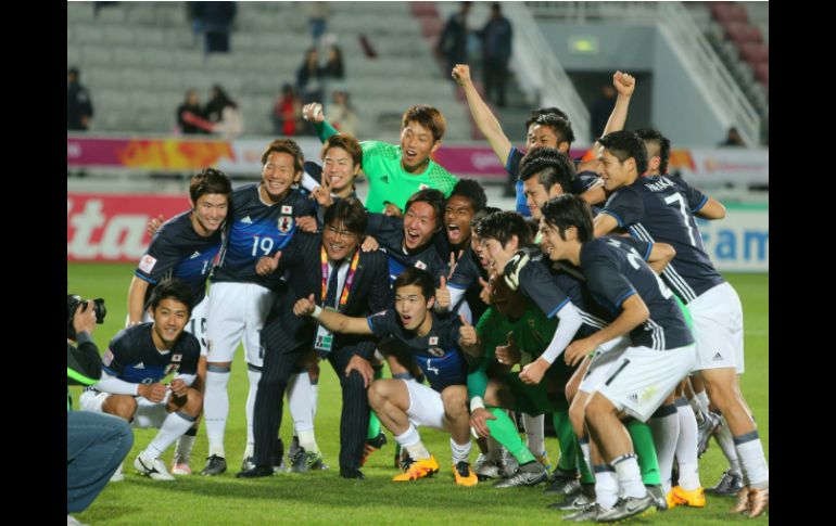 Jugadores japoneses celebran su victoria junto a su entrenador Makoto Teguramori (c-i). AFP / K. Jaafar