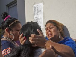 Tres mujeres lloran y tratan de consolarse después de leer el nombre de sus familiares en la lista de víctimas en Topo Chico. AFP / J. Aguilar