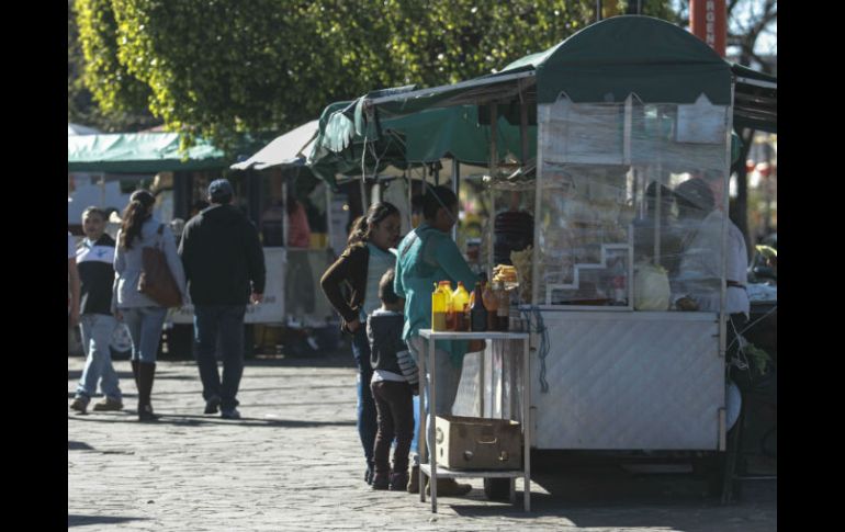 Clientes pasean por la Plaza Juan Pablo II y visitan los puestos de frituras y otros, en el Centro zapopano. EL INFORMADOR / F. Atilano