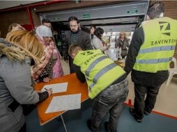 Varios pasajeros se registran ante dos empleados en un polideportivo donde se concentran los viajeros en Zaventem. EFE /  J. Roosens