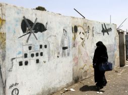 Una mujer camina junto a unas pinturas que se hicieron en protesta por los ataques con drones estadounidenses. EFE / Y. Arhab